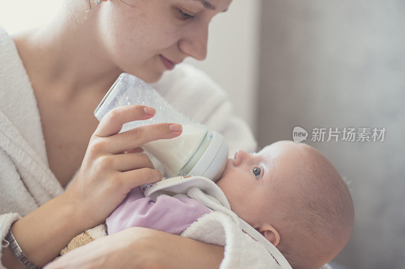 一个婴儿在母亲怀里喝牛奶的特写