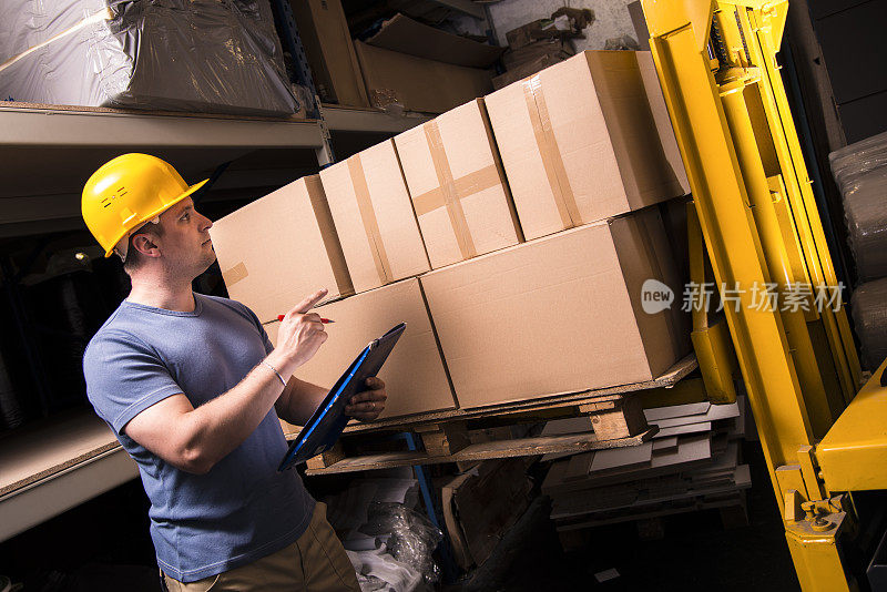 一个工人在仓库检查货物的图像