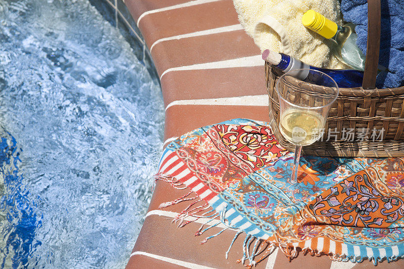 在度假村游泳池的篮子里放酒瓶和毛巾。