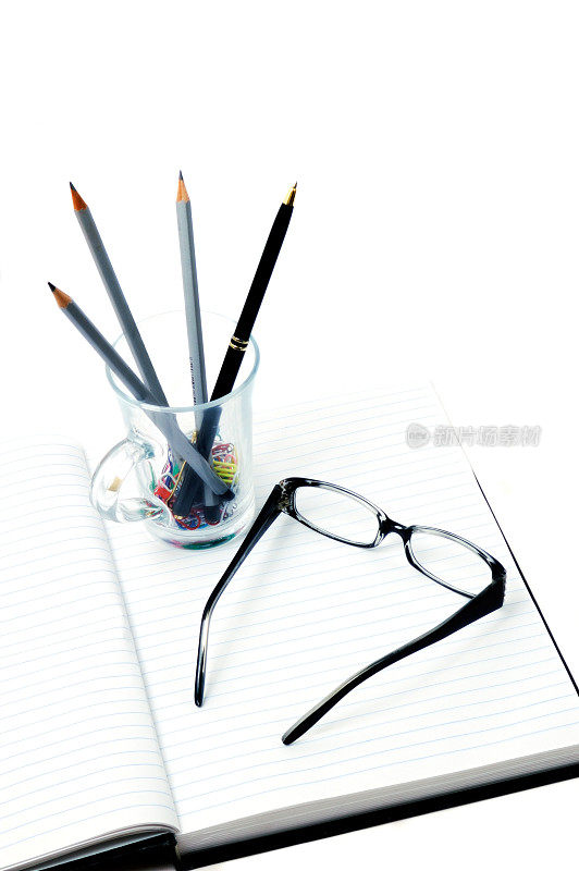 眼镜，钢笔，铅笔和夹子在笔记本上