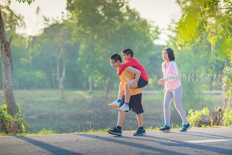 家庭运动快乐活跃的母亲和孩子在户外慢跑，在森林里跑步