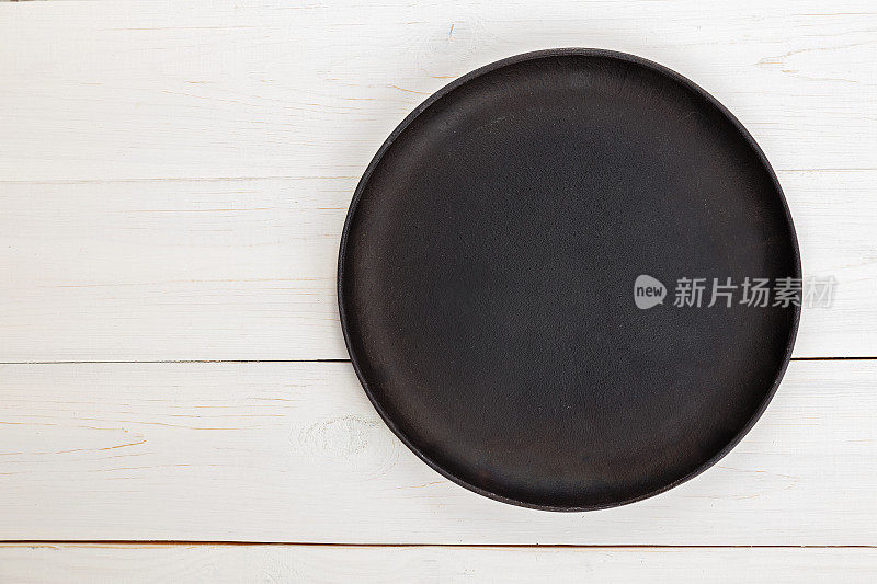 空的圆形铸铁煎锅比萨饼或馅饼在白色木制背景