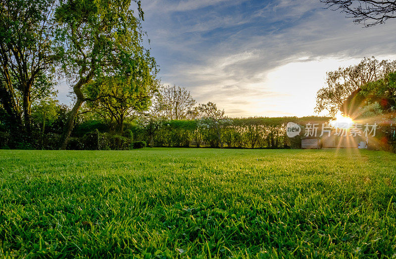 晚春壮丽的日落，显示了最近修剪和维护良好的大草坪在农村的位置。