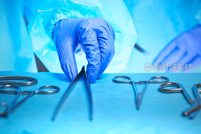 外科医生的双手在手术室工作的特写，色调为蓝色