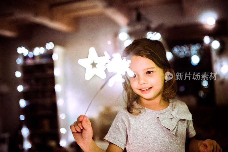圣诞节的时候，小女孩拿着闪闪发光的东西。