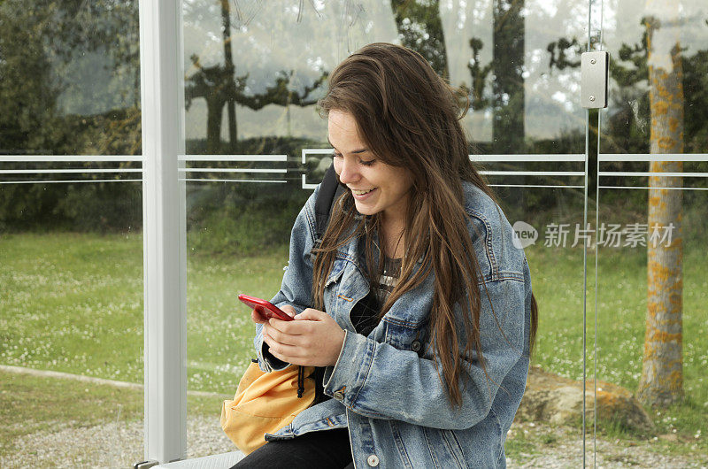 学生在公交车站使用手机