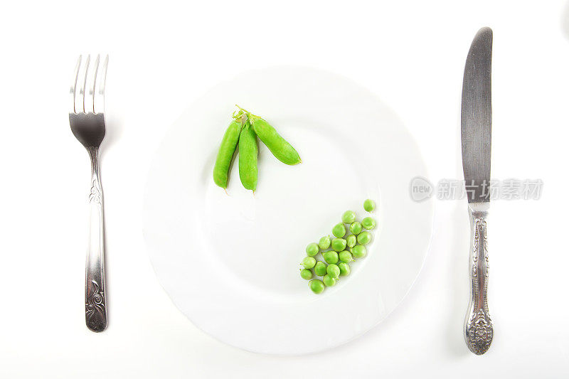 盘子里的豌豆和豆荚，刀叉分开放在白色背景上