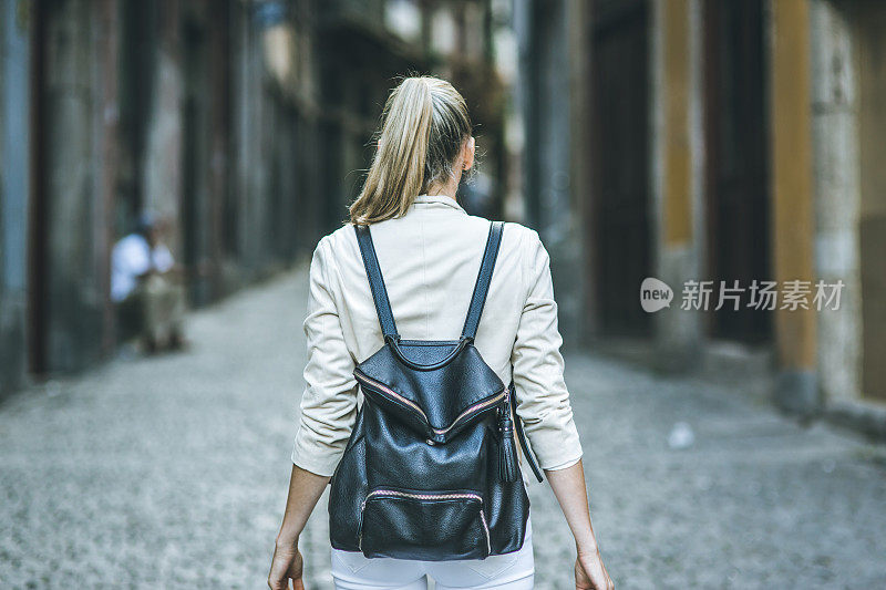 年轻女子背着背包走在欧洲的街道上