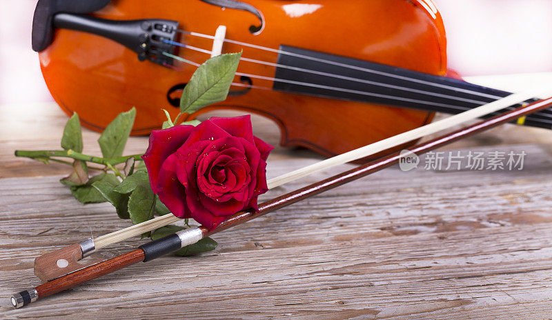 木桌上放着小提琴和红玫瑰