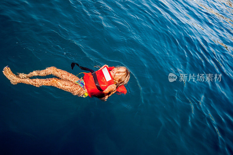 穿着救生衣在海里游泳的女孩