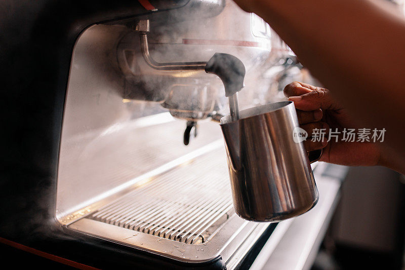 咖啡师在咖啡馆的咖啡机上蒸牛奶