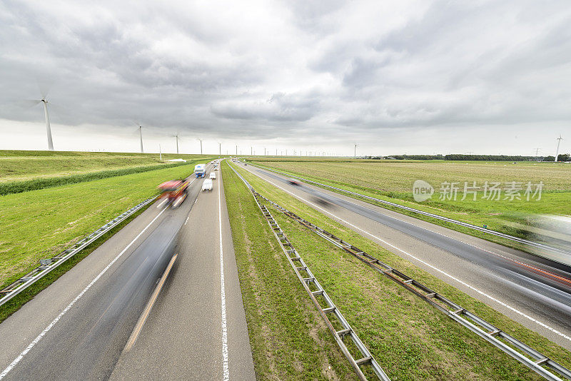 公路上的交通在一个开放的乡村景观与风力涡轮机