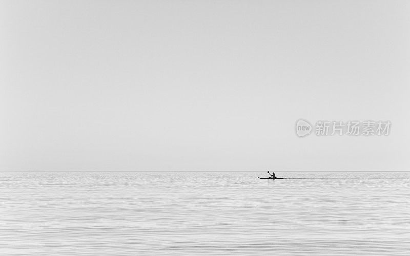 在平静的海面上划皮艇的人。下午早些时候，希腊爱琴海上的男子皮划艇。