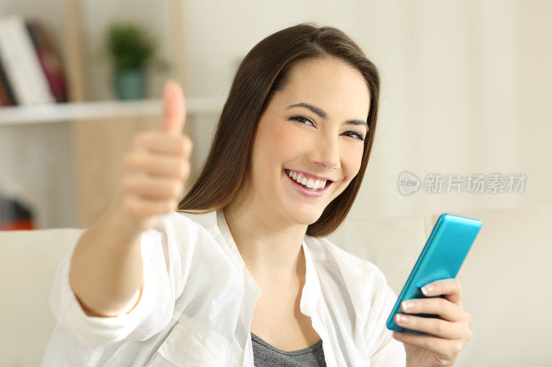 满意的女孩拿着智能手机，竖起大拇指