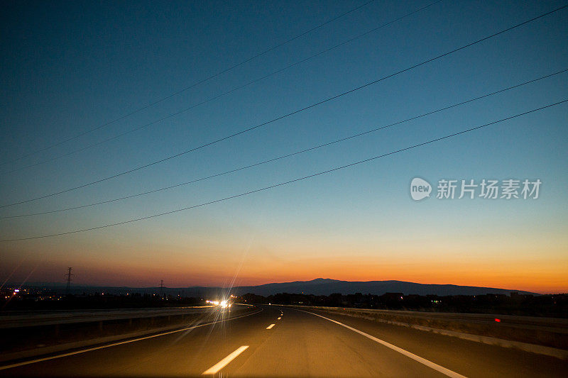 美丽的太阳冉冉升起的天空配以沥青路公路的乡村风光，利用陆路交通和旅行背景，作为背景