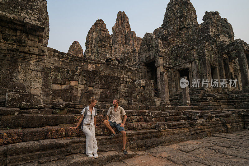 一对在亚洲旅游的游客，在夕阳下凝视美丽的古庙和古老的废墟;人发现探索理念