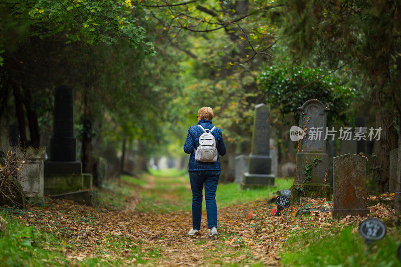 后视图lonley资深妇女走过墓地