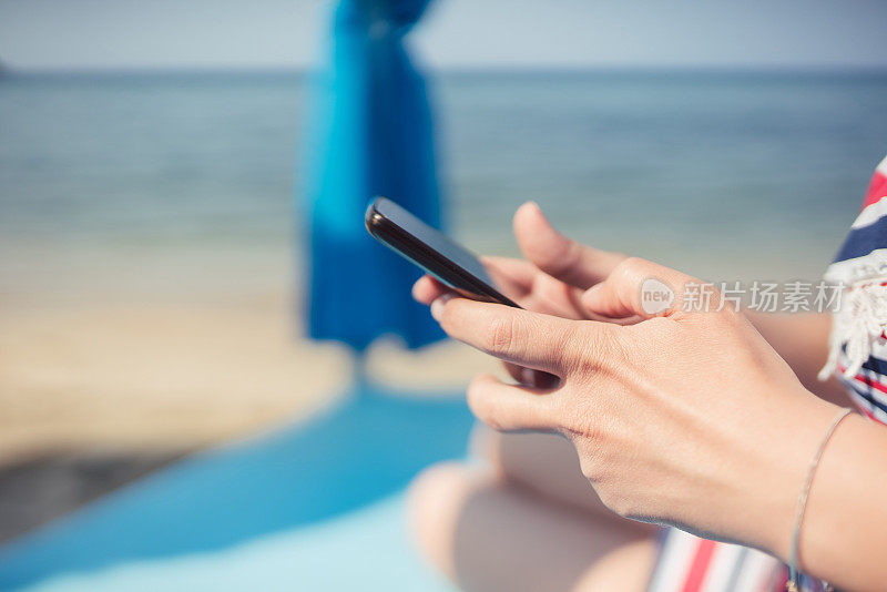 一个年轻女子在海滩上用手机