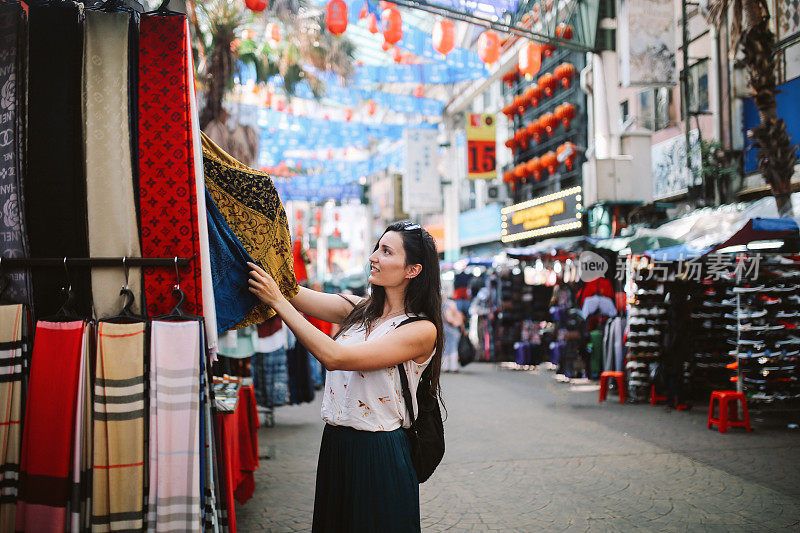 年轻的旅行者女人在吉隆坡唐人街区购物