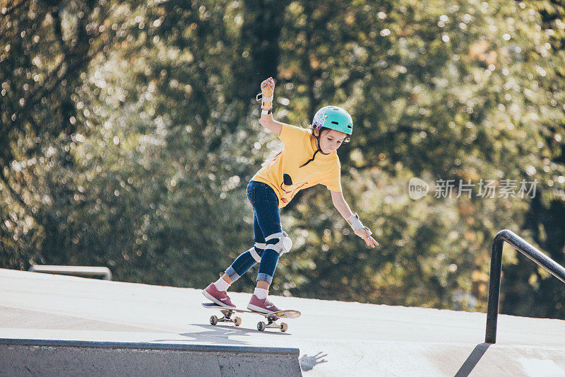 年轻女孩滑板在公共滑板公园