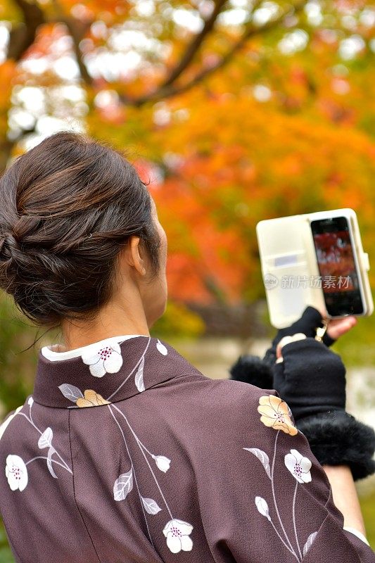 穿着和服的日本妇女在京都拍摄秋叶