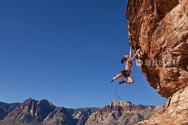 女性攀岩者紧紧抓住悬崖。