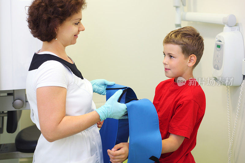 牙医戴着铅围裙给男孩做颌部x光检查