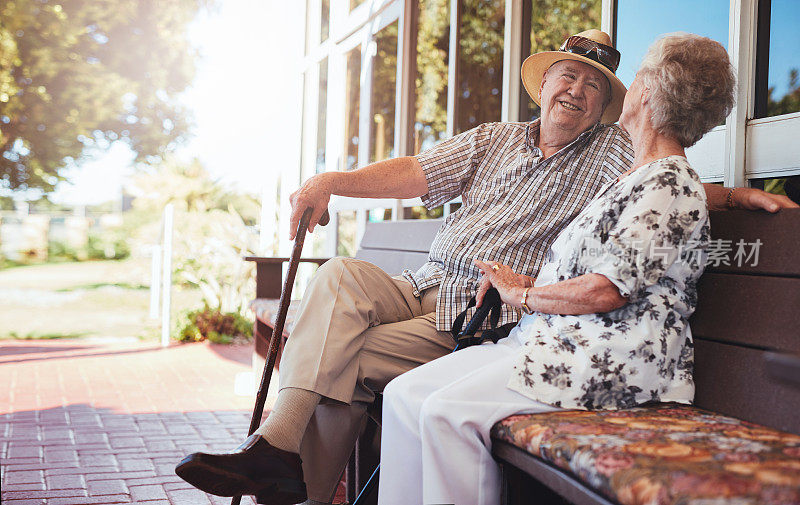 一对快乐的老夫妇在屋外的长椅上休息