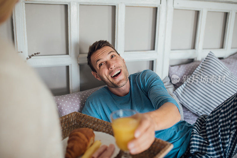 微笑的男人吃着早餐，喝着橙汁