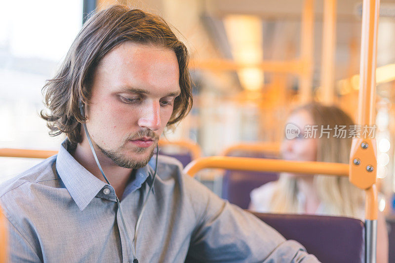 千禧年男性乘坐火车，用耳塞听播客