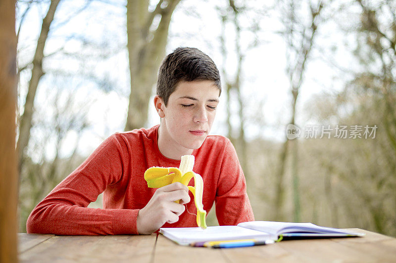 一个在城市公园里学习的少年。吃健康零食的时间到了