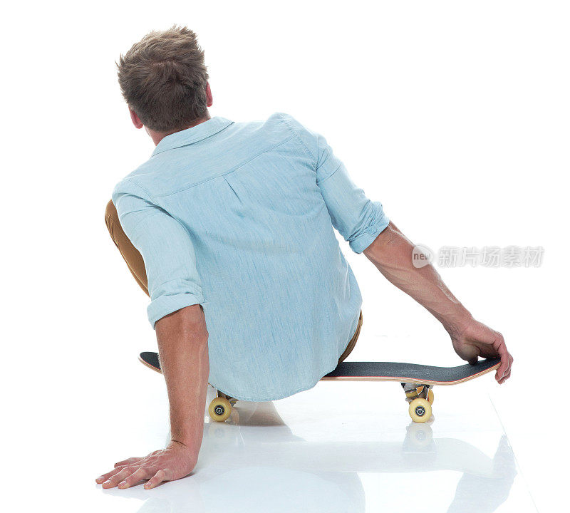 穿着随意，坐在滑板上的男人