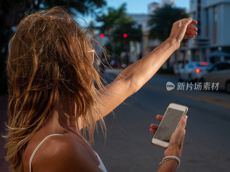 在智能手机上使用拼车应用的年轻女性，在城市街道上使用手机拼车应用的女孩，在线拼车或拼车服务。现代生活中的科技和交通