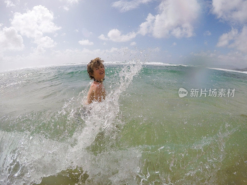 小男孩在夏威夷考艾岛玩，溅水，享受美丽的海水。