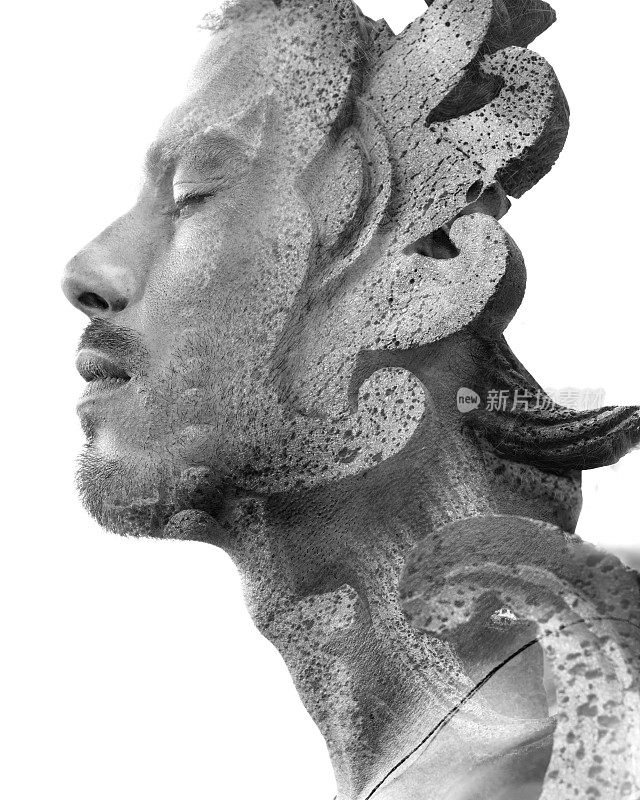 一个迷人的年轻男子的双重曝光近距离侧面肖像与一个纹理复杂的巴厘岛岩石雕像，黑色和白色