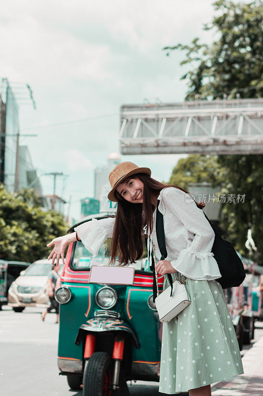 年轻的亚洲女孩旅行者在泰国曼谷叫一辆嘟嘟出租车。