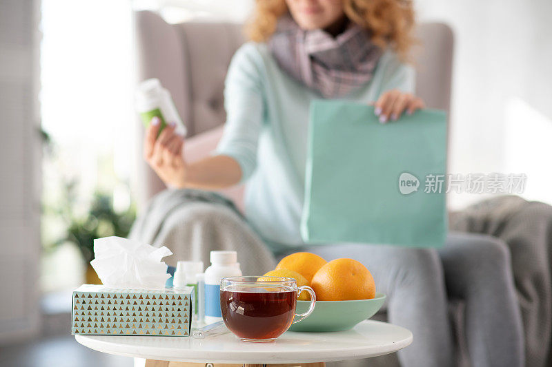一个得了流感的女人把橘子和茶放在桌子上