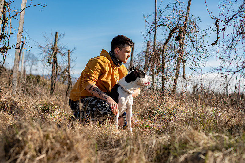 年轻的成年男子与他的狗在农村场景