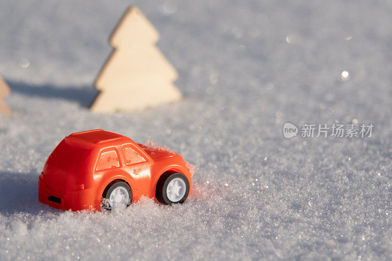 一辆玩具复古车在雪地里的轨迹。在汽车的后面有一个红色的新年球。极简主义理念，60年代风格。节日快乐贺卡