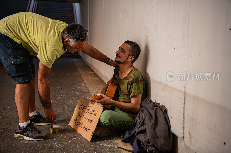 无家可归的乞丐正在接受一个好人的施舍