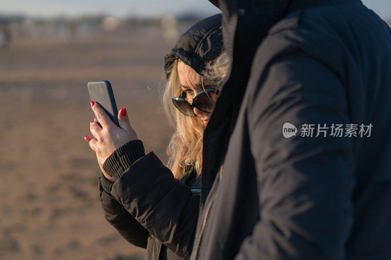 一个年轻女子在海滩上用手机