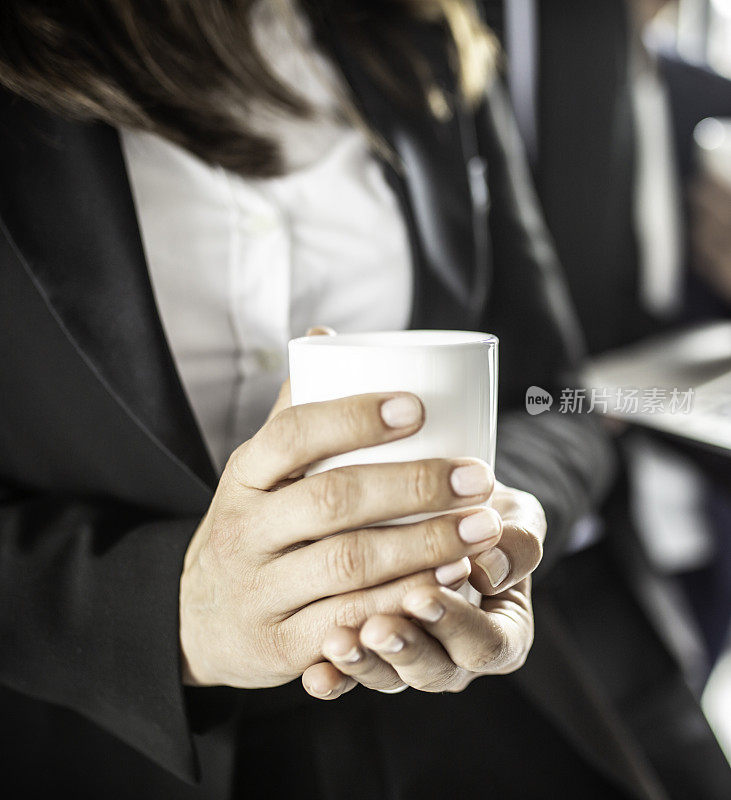 近距离的女商人持有一个咖啡杯库存照片