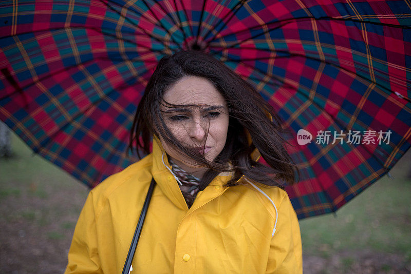 穿着黄色雨衣的年轻女子在公园里度过雨天