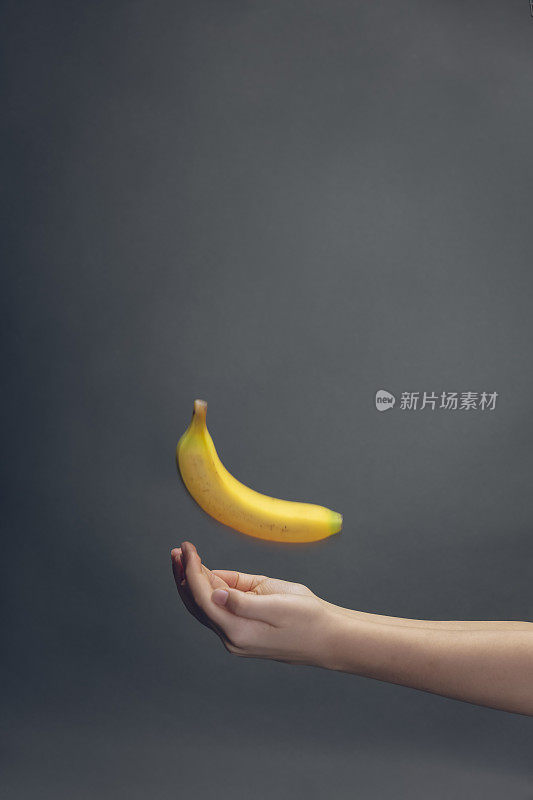 两个空的孩子的手抓香蕉在黑暗的背景与拷贝空间