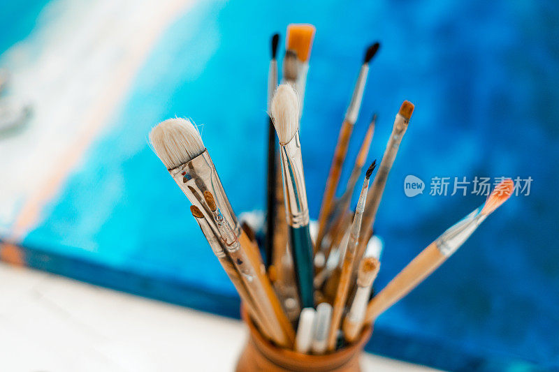艺术家的工具和设备。调色板和画笔特写。绘画和创造力的过程。这幅画是蓝色的。