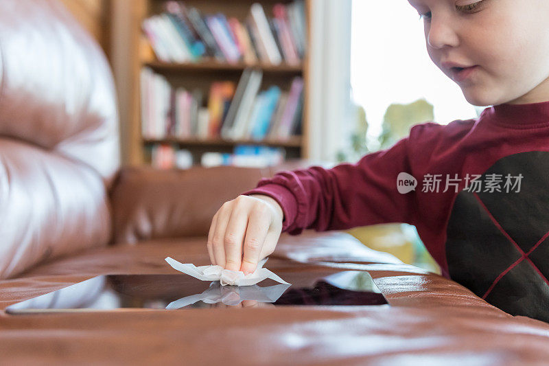 小男孩用抗菌一次性湿巾或纸巾清洗数码显示屏