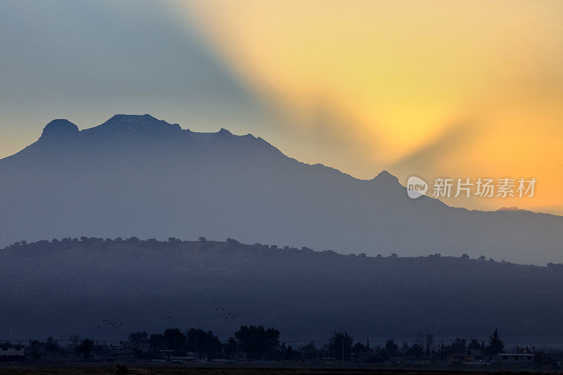 黎明出现在墨西哥城东南的伊塔奇瓦特火山后面