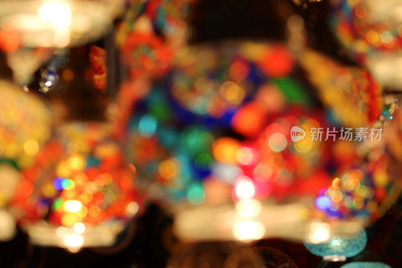 模糊的焦点图像许多色彩丰富，马赛克玻璃球灯悬挂在天花板上，映衬着黑暗的背景，照亮了发光的摩洛哥风格灯笼室内照明