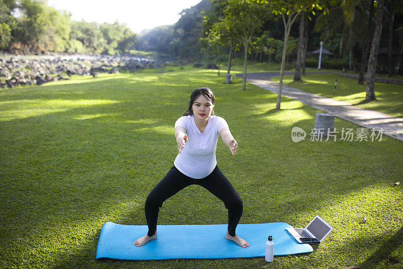 年轻的亚洲孕妇在公园里练习瑜伽