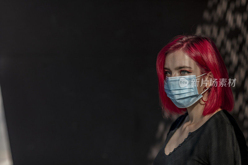 染红头发的年轻女子戴着面具